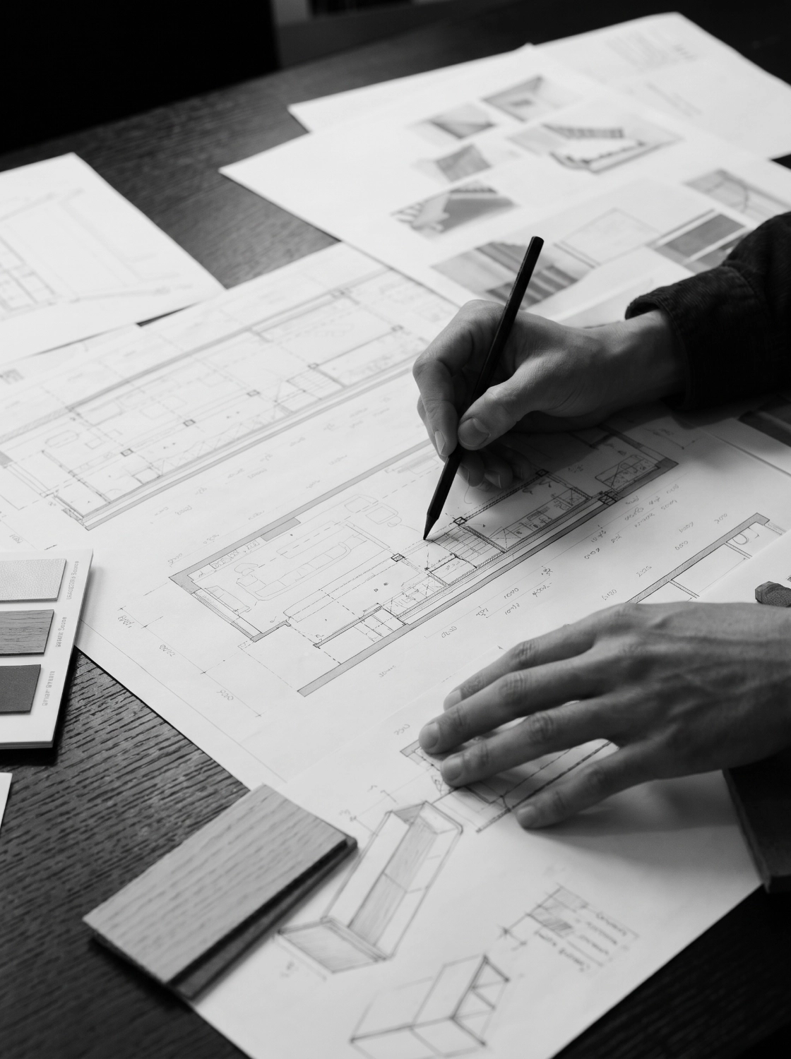 A designer working on architectural drawings and material references